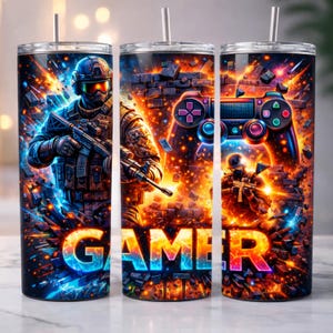 May include: A set of three stainless steel insulated tumblers with a vibrant gamer-themed design. Each tumbler features a soldier graphic, a game controller, and the word "GAMER" in colorful text against a background of explosions and digital effects.