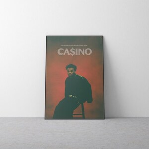 May include: A framed poster featuring a person seated on a stool. The poster has a red and green background with the word "CASINO" in large white letters. The text "THE SECOND STUDIO ALBUM BY BARRY WOOD" is at the top.