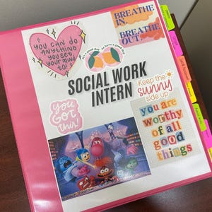 Pode incluir: Uma pasta rosa com a inscrição "SOCIAL WORK INTERN" e vários autocolantes. Os autocolantes incluem frases motivacionais e uma imagem colorida do filme Divertida Mente. A pasta também tem separadores coloridos para organização.