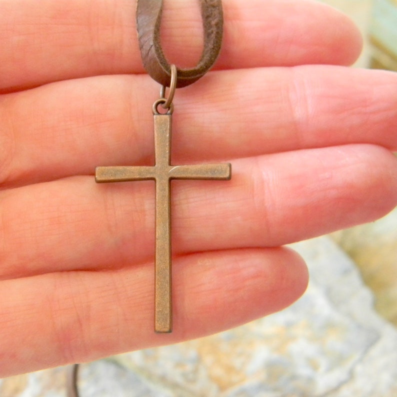 May include: A brown leather cord necklace with a bronze cross pendant.