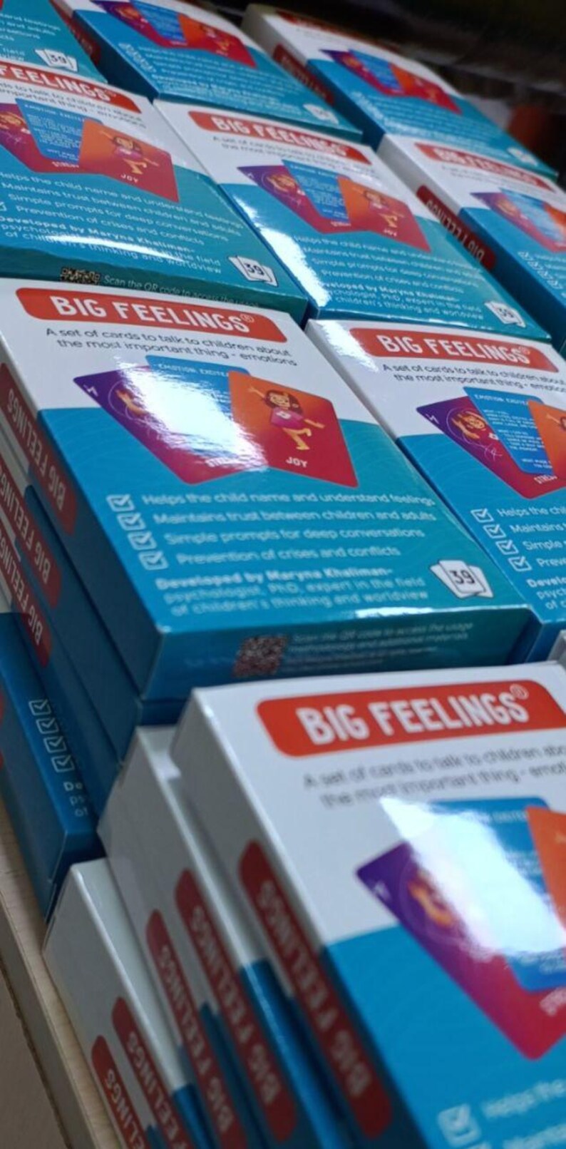 May include: Stacks of "Big Feelings" card sets. Each box features a red and white label with the product name and a blue background with product information. The cards are designed to help children understand emotions.