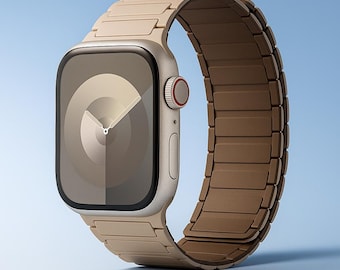 Puede incluir: Un reloj inteligente beige con una correa a juego. La esfera del reloj muestra un diseño radial claro con manecillas que indican la hora. La correa está hecha de eslabones rectangulares. El reloj tiene un botón rojo y un diseño elegante.