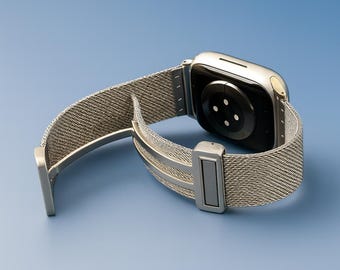May include: A silver smartwatch with a mesh band, displayed against a blue background. The watch's back is visible, showing sensors. The band is open, revealing the clasp mechanism. The watch case has a polished finish.