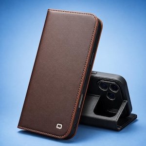 Puede incluir: Una funda tipo libro para teléfono en color marrón con textura lisa y costuras visibles en los bordes. La funda presenta un pequeño logotipo cuadrado en la parte inferior y un marco interior negro con un recorte para cámara de tres lentes.