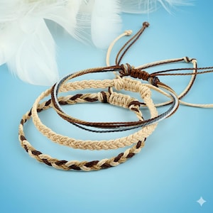 Puede incluir: Una colección de pulseras de la amistad tejidas en tonos marrón, beige y azul. Las pulseras están hechas de cordones trenzados y anudados, con cierres ajustables. El fondo es un degradado azul claro.