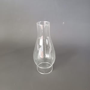 May include: A clear glass oil lamp chimney featuring a bulbous midsection that tapers into a narrow, cylindrical top opening and a wider, circular base designed for secure attachment to a lamp fixture, showcasing a smooth, transparent surface.