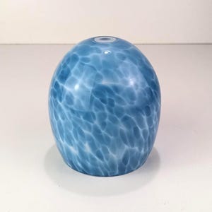 May include: A dome-shaped glass light shade featuring a mottled pattern of translucent white and various shades of blue. The surface has a smooth, glossy finish with a circular opening at the top center for a light fixture attachment.