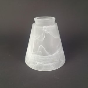 Peut inclure: Un abat-jour conique en verre présentant une finition blanche givrée avec de subtils motifs translucides tourbillonnants sur toute la surface. L'abat-jour possède une ouverture circulaire étroite en haut et une ouverture plus large à la base.