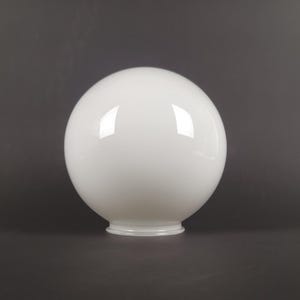 May include: A white, spherical glass lampshade with a glossy finish. The globe-shaped shade has a rounded base and reflects light. The background is a solid, dark gray.