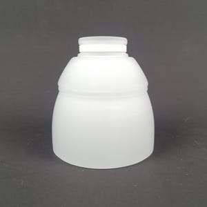 Op de afbeelding: Een matglazen lampenkap met een afgeronde body en een cilindrische bovenkant. De kap is ondoorzichtig wit en heeft een gladde, matte afwerking. De lampenkap is ontworpen om licht te verspreiden.