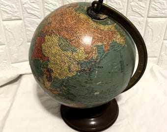 May include: A vintage globe with a brown base and a metal meridian. The globe features a map with various colors, including green, orange, and yellow, and is mounted on a dark brown stand. The globe is a decorative item.