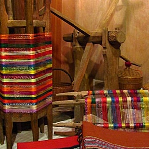 May include: A wooden loom with colorful threads and woven fabric. The loom is made of wood and has a hand crank. The fabric is woven with a variety of colors, including red, blue, green, and yellow.