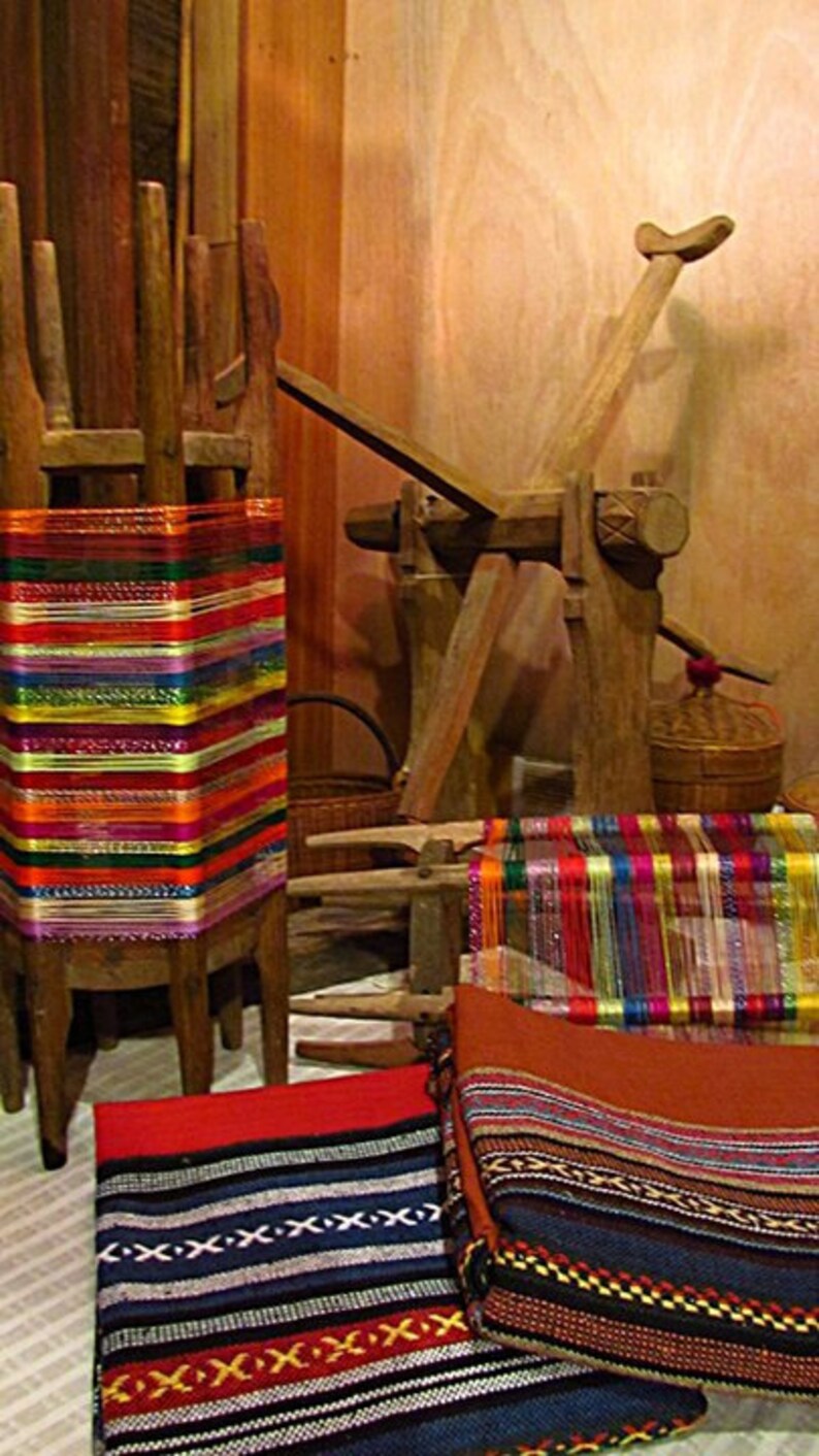 May include: A wooden loom with colorful threads and woven fabric. The loom is made of wood and has a hand crank. The fabric is woven with a variety of colors, including red, blue, green, and yellow.
