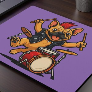 Peut inclure: Tapis de souris violet avec un bouledogue de dessin animé jouant de la batterie. Le bouledogue porte une veste en cuir noire et a une crête rouge. La batterie est rouge et or. Un ordinateur portable et une petite plante en pot sont en arrière-plan.