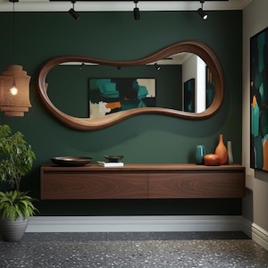 Op de afbeelding: Een modern interieur met een grote, organisch gevormde houten spiegel. Onder de spiegel een zwevende houten console met decoratieve items, waaronder vazen en een kom. De muur is diepgroen geschilderd en de vloer is grijs gespikkeld.