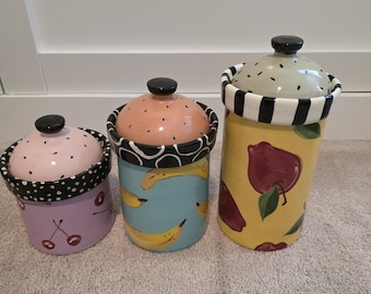 Juego de 3 botes pintados a mano de Droll Designs con diseño de frutas: manzana, plátano y cereza.