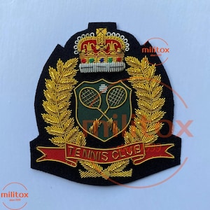 Op de afbeelding: Een zwart geborduurd embleem met een gouden kroon, tennisrackets en de tekst "TENNIS CLUB" op een rode banner. De patch heeft een gouden laurierkrans ontwerp, voor een tennisclub.
