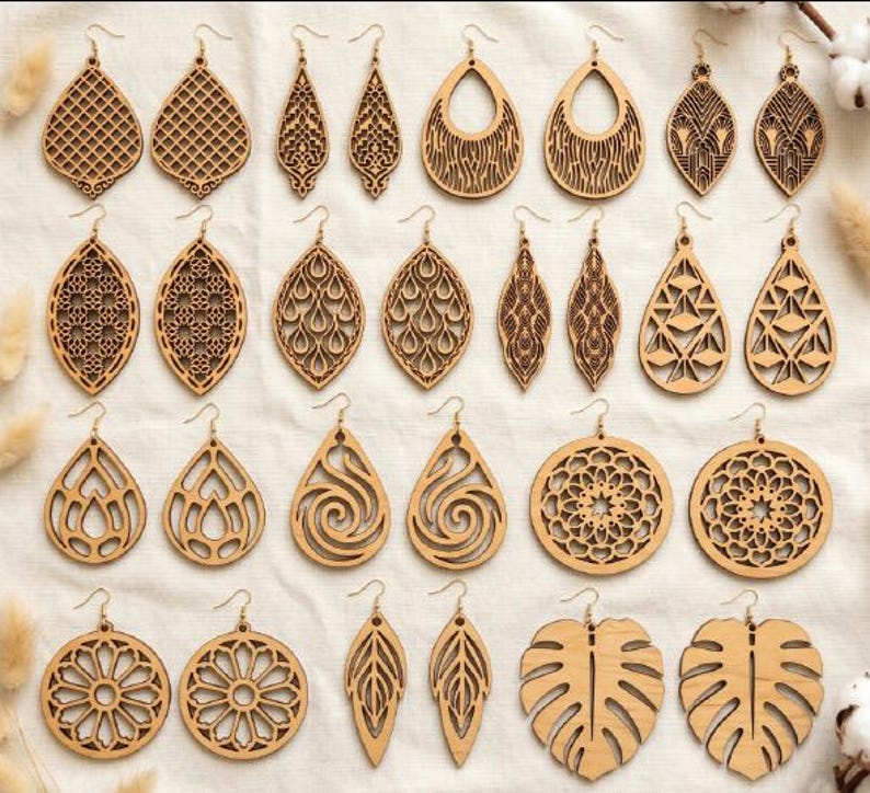 May include: A collection of twenty-eight wooden earrings arranged in fourteen pairs. The earrings feature various laser-cut designs including teardrop, circular, and leaf shapes with intricate geometric, floral, and swirling patterns.