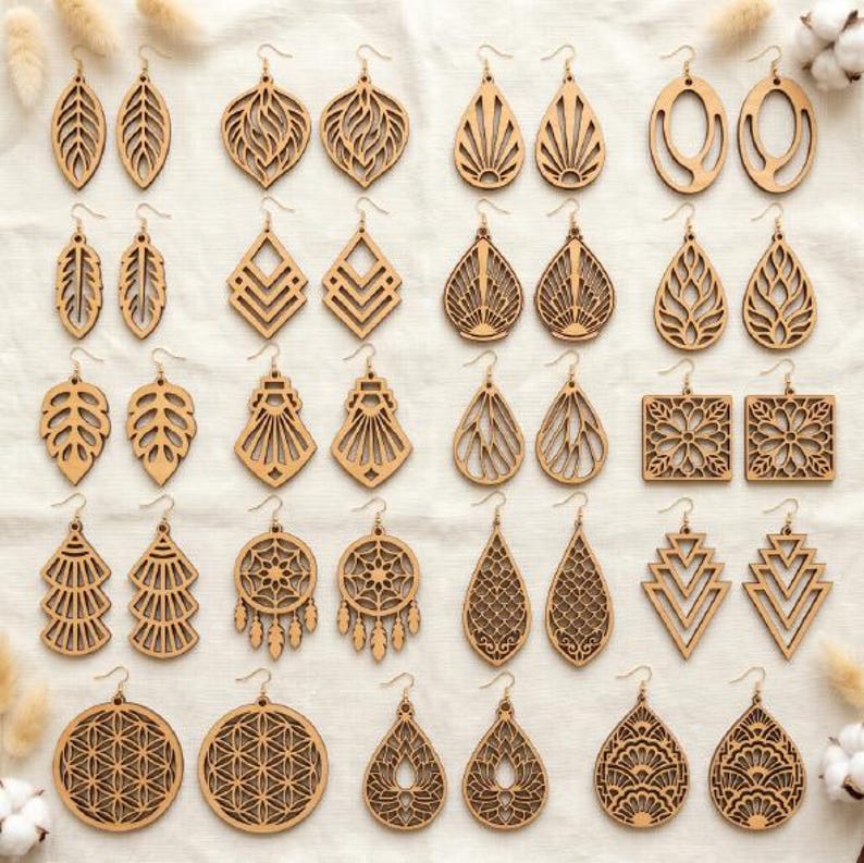 May include: A collection of twenty-five pairs of light brown wooden laser-cut earrings arranged in a grid. The earrings feature various geometric, floral, leaf, and mandala-inspired patterns with intricate cutouts, all suspended from metal earring hooks.