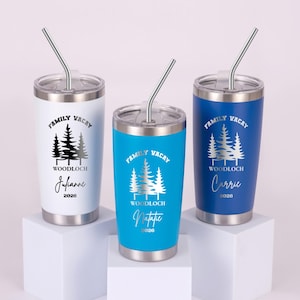 Puede incluir: Tres vasos de acero inoxidable con tapas y pajitas. Uno es blanco, otro turquesa y otro azul. Cada vaso tiene un gr&aacute;fico plateado de &aacute;rboles y las palabras "Family Vacay" y "Woodloch". Cada uno tiene un nombre y el a&ntilde;o 2026.