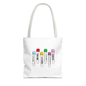 Peut inclure: Sac fourre-tout blanc avec un motif de six tubes à essai avec des bouchons colorés. Les tubes à essai ont des bouchons bleus, rouges, jaunes, verts, violets et roses. Le sac a une poignée blanche.