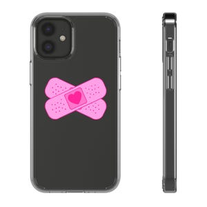 Peut inclure: Coque de téléphone transparente avec intérieur noir et motif pansement rose. Le motif présente deux pansements superposés avec un cœur au centre. La coque est conçue pour un smartphone.