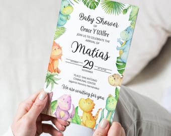 Puede incluir: Una invitación para un baby shower con dinosaurios en acuarela y hojas tropicales. La invitación incluye el texto "Baby Shower of Grace Y Wilfre" y detalles del evento, incluido el nombre "Matías" y la fecha del 29 de noviembre.