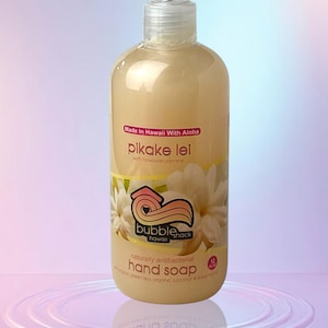 Peut inclure: Bouteille transparente de savon pour les mains avec un distributeur à pompe. L'étiquette indique "pikake lei" avec "Made in Hawaii With Aloha". L'étiquette présente également un logo avec un cœur et une fleur. La bouteille contient 355 ml de savon.