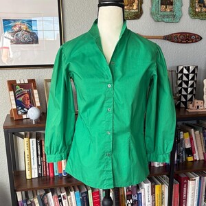 May include: A bright green button-down shirt with long sleeves. The shirt has a mandarin collar and is displayed on a mannequin. The fabric appears to be a lightweight cotton or blend. The shirt is a solid color and has a tailored fit.