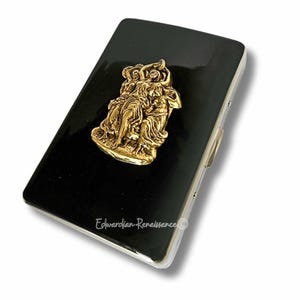 May include: A black rectangular case with a gold-colored relief of figures. The case has a shiny, reflective surface and a silver-colored border. The text "Edwardian-Renaissance" is printed on the bottom.