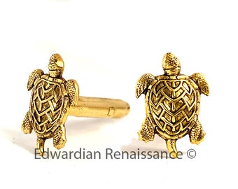 May include: A pair of gold-tone cufflinks featuring a detailed turtle design. The cufflinks are made of metal and have a polished finish.
