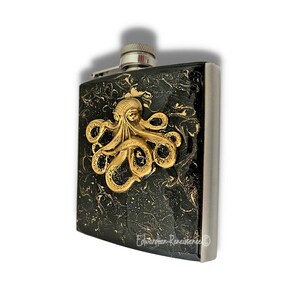May include: A black and gold stainless steel flask with an octopus design. The flask has a marbled black and gold finish with a gold octopus design.