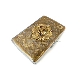 Estuche para cigarrillos con forma de cabeza de león, esmaltado en oro pintado a mano, diseño Art Déco inspirado en Leo, con opciones de color y personalización.