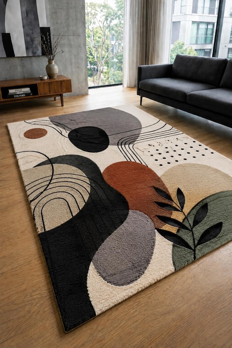 Puede incluir: Una alfombra rectangular con un dise&ntilde;o abstracto de formas org&aacute;nicas en tonos negro, gris, naranja &oacute;xido, beige y verde salvia. El patr&oacute;n incluye l&iacute;neas negras finas, un grupo de puntos peque&ntilde;os y un motivo de hoja de color negro.