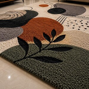 Puede incluir: Una alfombra texturizada con un patr&oacute;n abstracto de formas org&aacute;nicas en tonos naranja &oacute;xido, verde oliva, gris carb&oacute;n y crema. El dise&ntilde;o incluye una silueta de hoja negra y l&iacute;neas finas sobre una superficie de pelo alto y copetuda.