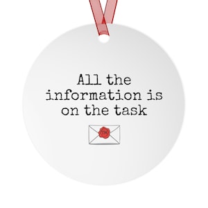 May include: A white, round Christmas ornament with the text "All the information is on the task" in black. A small envelope graphic with a red wax seal is below the text. A red ribbon is attached for hanging.