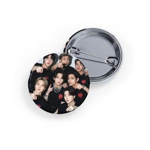 以下が含まれることがあります： 黒いシャツを着た7人のグループの写真がプリントされた丸い缶バッジ。 バッジは、安全ピン留め付きの銀色の金属製の裏面が付いています。 バッジの画像は写真です。