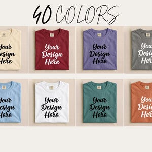 May include: A selection of folded t-shirts in various colors, each displaying the text "Your Design Here" in a bold, black font. The image is labeled "40 COLORS" at the top, showcasing a range of options for custom designs.