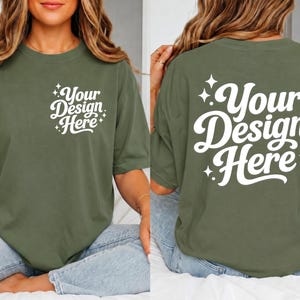 May include: Olive green t-shirt with the text "Your Design Here" in white script on the front and back. The design is surrounded by starburst accents. The shirt has short sleeves and a relaxed fit.