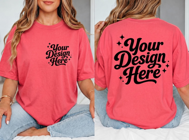 May include: Coral-colored t-shirt with the text "Your Design Here" in a black script font on the front and back. The shirt has short sleeves and a relaxed fit. The text is surrounded by small starburst designs.
