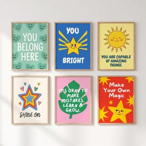 Può includere: Sei stampe artistiche da parete incorniciate con illustrazioni colorate e testo. Le stampe includono un motivo a cuori verde menta con 'YOU BELONG HERE', una stella blu con 'YOU BRIGHT', un sole giallo con 'YOU ARE CAPABLE OF AMAZING THINGS', una stella con 'SHINE ON', una foglia verde con 'IT'S OKAY TO MAKE MISTAKES. LEARN & GROW', e uno sfondo rosso con 'Make Your Own Magic' e una stella gialla.