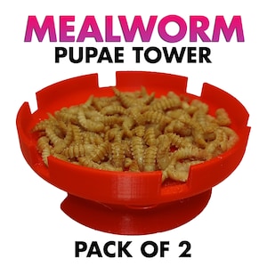 May include: A red plastic Mealworm Pupae Tower filled with mealworms. The text "MEALWORM PUPAE TOWER" is displayed above the tower in pink and black. The text "PACK OF 2" is displayed below the tower in black.