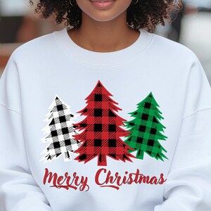 May include: White crew neck sweatshirt featuring three Christmas trees in black and white, red, and green plaid patterns. The words "Merry Christmas" are written in red script below the trees.