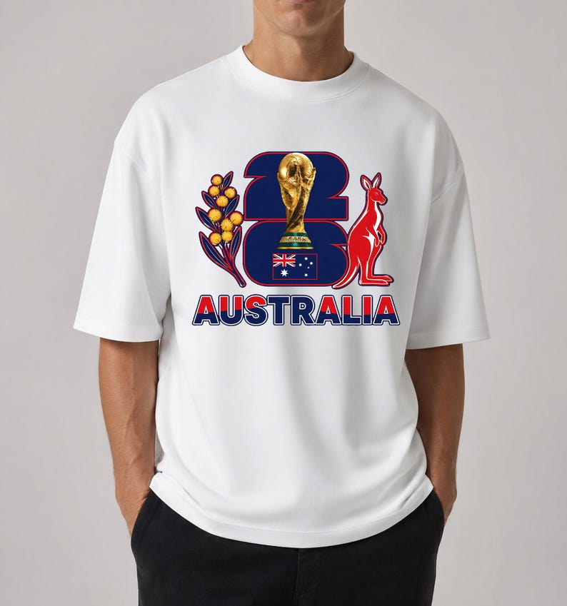 Puede incluir: Camiseta blanca con un dise&ntilde;o gr&aacute;fico que presenta el n&uacute;mero '23' en azul marino, un trofeo dorado, un canguro rojo y la palabra 'AUSTRALIA' en rojo y azul. El dise&ntilde;o incluye una ramita con bayas amarillas.