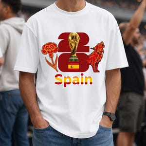 Puede incluir: Camiseta blanca con un dise&ntilde;o gr&aacute;fico que presenta un trofeo dorado, un clavel rojo y un lobo rojo aullando. La palabra "Espa&ntilde;a" se muestra en rojo y amarillo. La camiseta la lleva una persona.