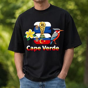 Puede incluir: Camiseta negra con un dise&ntilde;o que incluye el texto "Cape Verde", un trofeo dorado, un p&aacute;jaro y una flor. El dise&ntilde;o incorpora los colores de la bandera de Cabo Verde. La camiseta es de estilo casual y de manga corta.