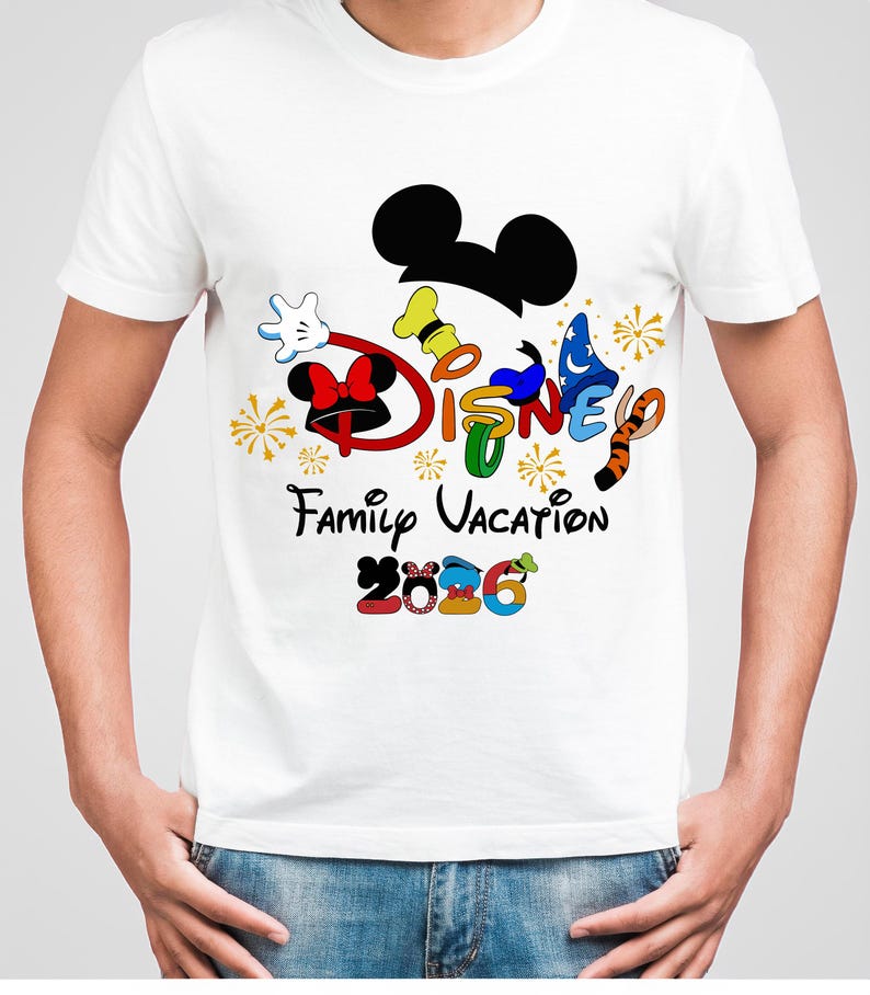 May include: White t-shirt featuring a colorful Disney design. The design includes Mickey Mouse ears, the word "DISNEY" in various colors, and the text "Family Vacation 2026". The shirt has a crew neck and short sleeves.
