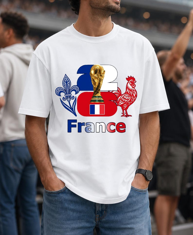 Puede incluir: Camiseta blanca con un dise&ntilde;o gr&aacute;fico que celebra a Francia. El dise&ntilde;o incluye un trofeo dorado, un gallo rojo, la bandera francesa y la palabra "France" en azul. La camiseta la lleva una persona con vaqueros azules.