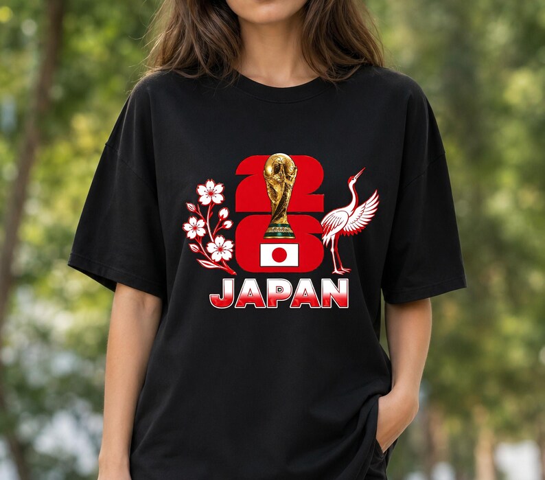 Puede incluir: Camiseta negra con un dise&ntilde;o gr&aacute;fico que dice "2023 JAP&Oacute;N". El dise&ntilde;o incluye un trofeo dorado, la bandera japonesa, flores de cerezo y una grulla. Es una prenda de vestir informal.