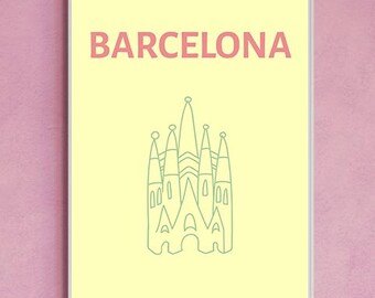 May include: A framed print featuring the word "BARCELONA" in coral-colored text above a green line drawing of a cathedral. The print has a light yellow background and a gray border, set against a pink backdrop.